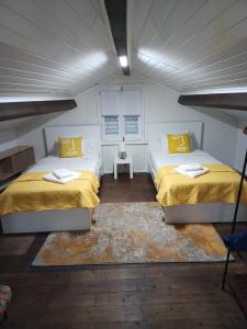 two beds in a room with yellow pillows at AL Boca da Canada in Água de Alto