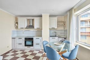 Una cocina con una mesa de cristal y sillas azules. en Beach Front Luxury Apartment, en Sozopol