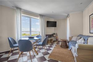 Una sala de estar con un sofá y una mesa con sillas. en Beach Front Luxury Apartment, en Sozopol