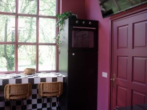 a kitchen with a black refrigerator and a pink wall at Stay Classy - Tiny House in Otterlo