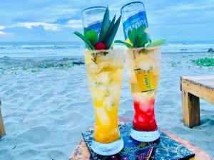 two cocktails in glasses sitting on the beach at Ecohotel Kocoluu in San Bernardo del Viento