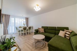 een woonkamer met een groene bank en een tafel bij Frida Luxury Apartments in Šiauliai +36 foto's