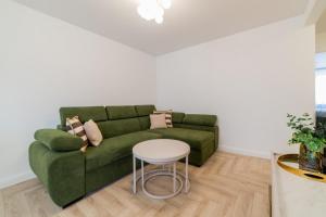 een woonkamer met een groene bank en een witte tafel bij Frida Luxury Apartments in Šiauliai