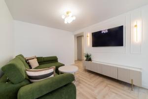 een woonkamer met een groene bank en een tv bij Frida Luxury Apartments in Šiauliai