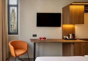 Una habitación de hotel con un escritorio y un televisor. en Regente Hotel, en Madrid
