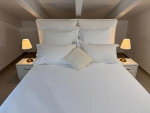 a large white bed with white pillows and two lamps at Sea View Loft Meta Sorrento Coast Free Parking in Meta