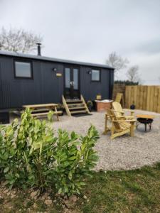 a black tiny house with a picnic table and chairs at Brackenslack Shepherds Huts in Maulds Meaburn