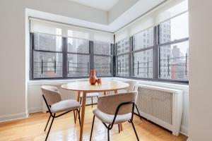 Una mesa y sillas en una habitación con ventanas. en Blueground Sutton Pl gym wd nr UN HQ NYC-1808, en Nueva York