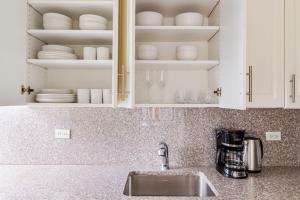 encimera de cocina con fregadero y armarios blancos en Blueground Sutton Pl gym wd nr UN HQ NYC-1808, en Nueva York 24 fotos más