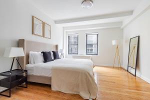 Un dormitorio blanco con una cama grande y dos ventanas. en Blueground Sutton Pl gym wd nr UN HQ NYC-1808, en Nueva York