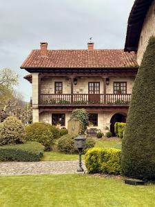 a large stone house with a balcony on a yard at Apartamentos Villa Julieta in Ruente