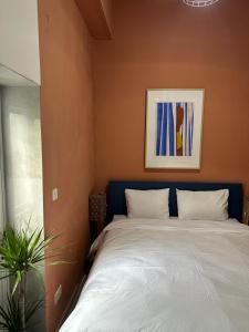 ein Schlafzimmer mit einem Bett und einem Gemälde an der Wand in der Unterkunft Follow the Sun Boutique Hostel - Pool, Breakfast & Sea Views in St Julian's
