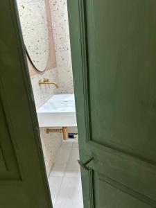 ein Badezimmer mit Waschbecken und grüner Tür in der Unterkunft Follow the Sun Boutique Hostel - Pool, Breakfast & Sea Views in St Julian's