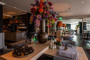 um restaurante com uma mesa com um grande vaso de flores em Golden Tulip Leiden Centre em Leiden
