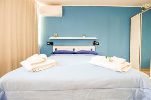 a blue bedroom with a white bed with towels on it at La Casetta sul Mare in Isola delle Femmine