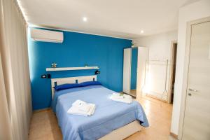 a blue bedroom with a bed with towels on it at La Casetta sul Mare in Isola delle Femmine