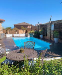 Un patio con mesa y sillas junto a una piscina. en Nautilus Guesthouse, en Port Elizabeth
