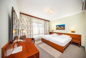 a hotel room with a bed and a desk at Wellness Hotel Happy Star in Hnanice