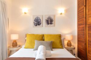 a bedroom with a bed with yellow pillows and two lamps at Quaint 2BDR beach apartment in a fishing village in Grand Gaube
