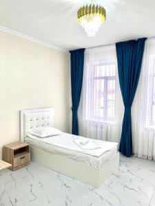 a bedroom with a bed with blue curtains and a chandelier at New hotel BEKARYS in Astana