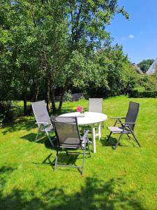 3 Stühle und ein Tisch im Gras in der Unterkunft Haus MeerZeit in Cuxhaven