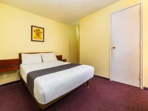a bedroom with a large white bed and a door at Capital O Hotel Suites Marne, Mexico City in Mexico City