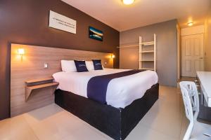 a bedroom with a large bed and a table at Collection O Hotel Mango,Six Flags Hurricane Harbor Oaxtepec in Oaxtepec