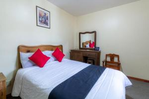 a bedroom with a bed with red pillows and a mirror at Capital O Hospedaje Los Angeles San Cristobal De Las Casas in San Cristóbal de Las Casas