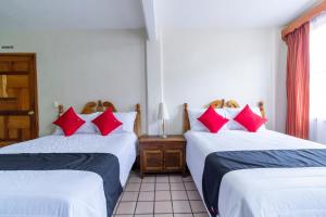 two beds in a room with red pillows at Capital O Hospedaje Los Angeles San Cristobal De Las Casas in San Cristóbal de Las Casas