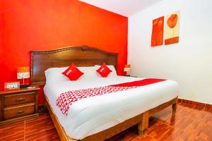 a bedroom with a large bed with red walls at OYO Posada De Los Angeles, Pátzcuaro in Pátzcuaro