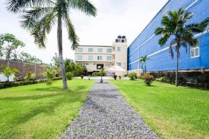 a gravel path in front of a building with palm trees at Capital O Hotel Los Caracoles, Acapulco in Acapulco