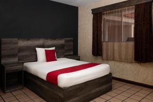 ein Schlafzimmer mit einem großen Bett und einem roten Kissen in der Unterkunft OYO Hotel Real Del Sur, Estadio Chihuahua in Chihuahua