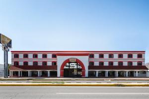ein rot-weißes Gebäude mit einem Bogeneingang in der Unterkunft OYO Hotel Real Del Sur, Estadio Chihuahua in Chihuahua
