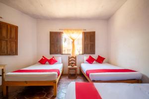 a room with two beds with red pillows and a window at OYO Cabañas Abril, Mazunte in Mazunte