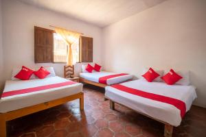 two beds in a room with red pillows on them at OYO Cabañas Abril, Mazunte in Mazunte
