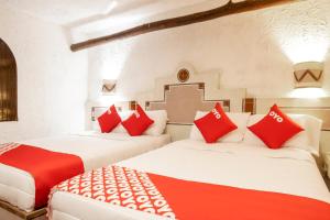 two beds in a room with red and white pillows at OYO Posada Astrud,Cuetzalan in Cuetzalán del Progreso