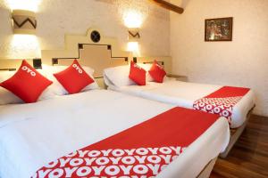 two beds in a room with red and white pillows at OYO Posada Astrud,Cuetzalan in Cuetzalán del Progreso