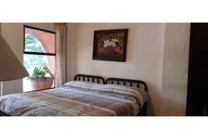 a bed in a bedroom with a picture on the wall at Capital O Posada Del Pescador Jocotepec in Chapala