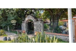 a stone archway in a park with a tree at Capital O Posada Del Pescador Jocotepec in Chapala +52 photos