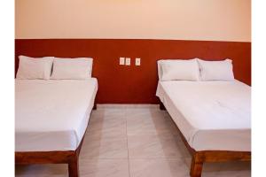 two beds sitting next to each other in a room at OYO Hotel La Playa in Zihuatanejo