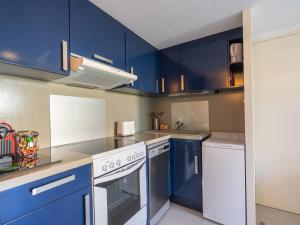 a kitchen with blue cabinets and white appliances at Holiday Home Les Jardins de l'Océan-38 by Interhome in Pontaillac +16 photos