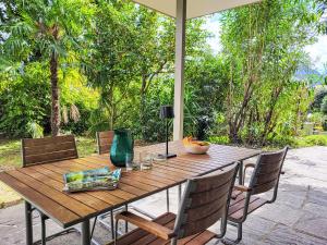 a wooden table with chairs and an umbrella on a patio at Apartment App- Castausio 26 by Interhome in Lugano