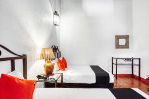 a bedroom with two beds and a table with a lamp at Capital O El Nito Posada in Oaxaca City