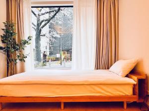 a bed in a room with a window at 新上双卧套房 最大5人 设计师风格Yaof 东京中心上野公园3分钟 车站1分钟 位置极佳超级繁华 房间内看樱花 in Tokyo