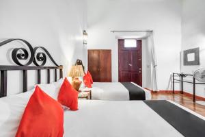 a bedroom with two beds with red pillows at Capital O El Nito Posada in Oaxaca City