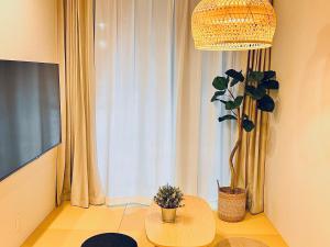a living room with a table and a potted plant at 新上双卧套房 最大5人 设计师风格Yaof 东京中心上野公园3分钟 车站1分钟 位置极佳超级繁华 房间内看樱花 in Tokyo +23 photos
