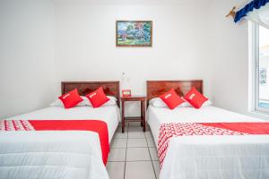two beds in a room with red pillows at OYO Hotel Posada San Vicente, Huatulco in Santa Maria Huatulco