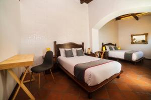 a bedroom with two beds and a table and a desk at Collection O Al otro lado del rio, Puebla in Puebla