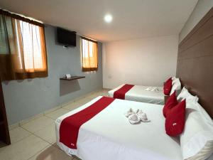 a hotel room with two beds with red and white sheets at OYO Hotel Familiar Tollan Cholula in Cholula