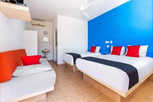 two beds in a room with blue and red pillows at Capital O Hotel El Mejicano, Acapulco in Acapulco